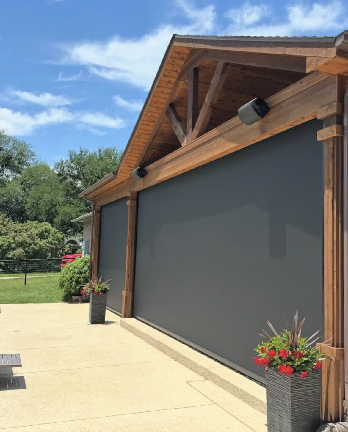 Motorized patio screens under a peaked-roof patio beside a pool