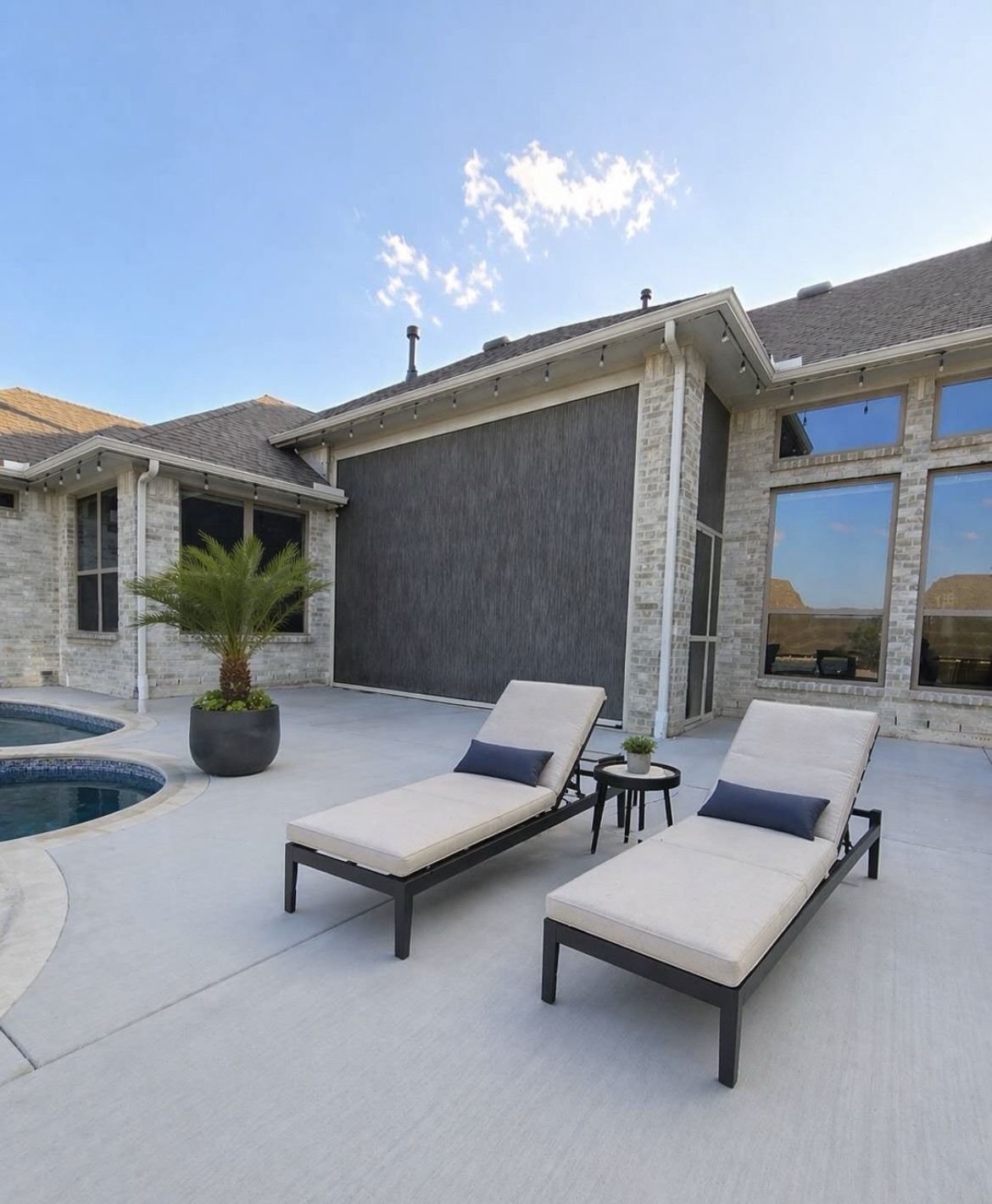 Shaded patio with lounge chairs behind motorized screens