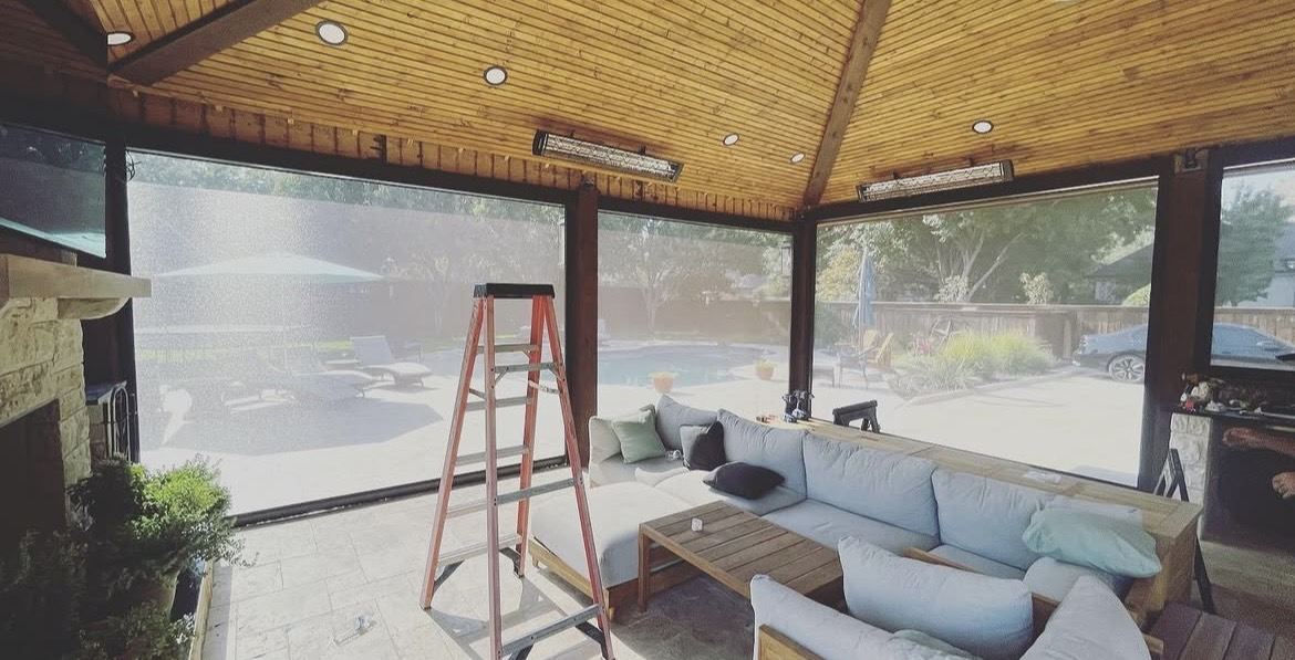 Wide covered patio with furniture behind motorized screens