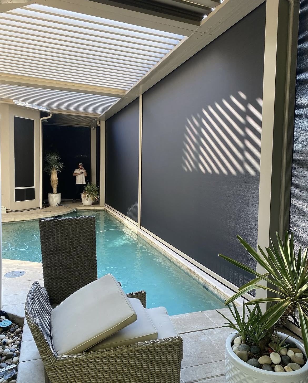Lowered motorized screens beside a backyard pool