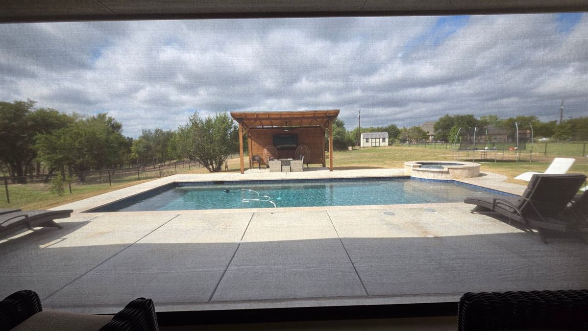 View through Nano 95 Tobacco screen fabric from inside the patio looking out at the pool and pergola