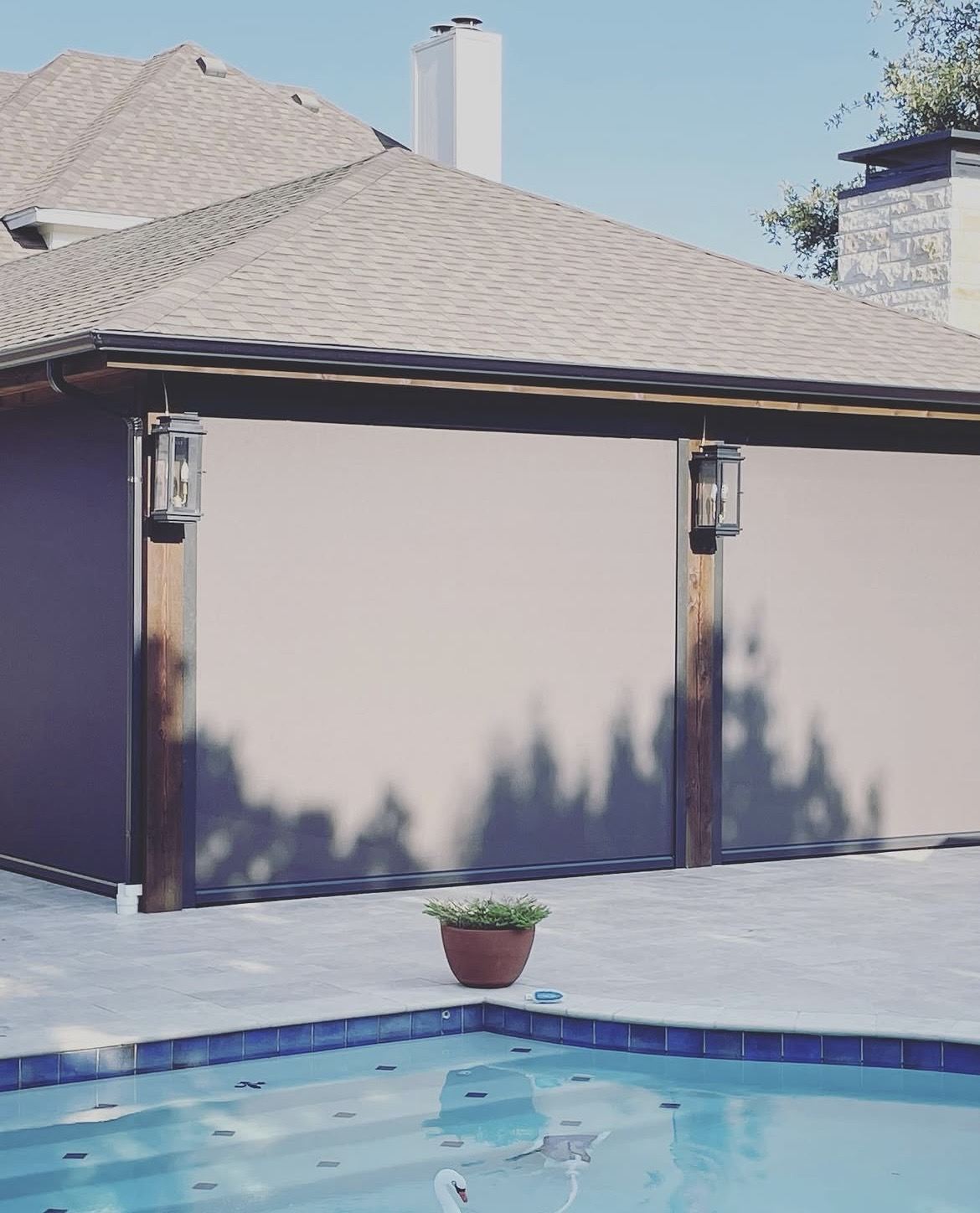 Lowered motorized screens giving a poolside patio instant privacy